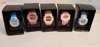 Front view of five boxed digital watches displaying colors and packaging