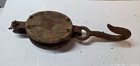 Full view of wooden pulley with iron hook