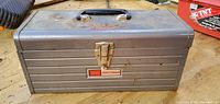 Front view of gray Craftsman metal toolbox showing latch, handle, logo