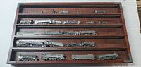 Full view of wood display case with pewter locomotives on five shelves