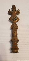 Full front view of brass winged female finial