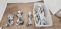 Overview of rubber-banded bundles of forks and spoons beside plastic bin of mixed flatware