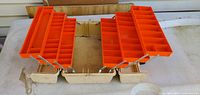 Tackle box open displaying two orange cantilever tray assemblies with many compartments