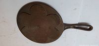 Underside of cast iron skillet showing ridged flower pattern and overall wear