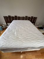 Mattress on box spring with wood headboard front view