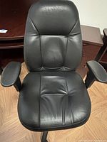 Front view of black faux leather swivel chair showing seat, backrest, armrests