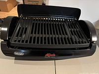 Front view of DeLonghi Alfredo Healthy Grill showing grill grate and logo