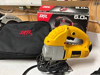 Front view of DeWalt DW317 jigsaw, SKIL bag and box visible
