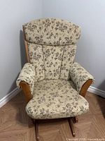 Front view of Dutailier glider rocker showing beige floral upholstery and wooden frame