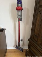 Full view of Dyson cordless stick vacuum on wall dock