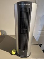 Front view of silver and black tower fan with tennis ball for scale