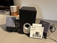Full view of subwoofer, two satellite speakers, cabling and manual