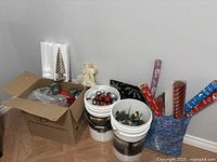 Overall lot: cardboard box, two white buckets of ornaments, rolls of wrapping paper