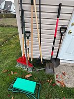 All tools leaning against siding with kneeler on grass