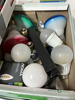 Box with assorted loose bulbs: colored floods, A19 LEDs, CFL