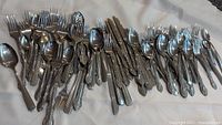 Full view of mixed flatware pile showing variety of utensils and ornate handle pattern