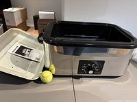 Roaster oven with lid, inner pan, rack, manual visible.