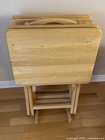 Front view of four folded tray tables on stand