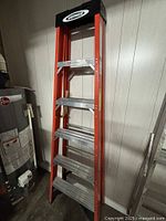 Full view of closed 6-ft Werner fiberglass ladder leaning against wall