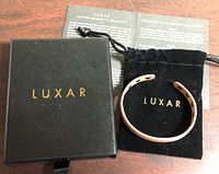 Bracelet in velvet pouch beside branded box and info card
