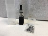 Tubular lock pick standing beside plastic storage tube and accessory pack