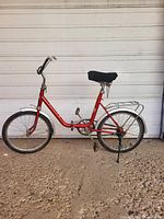 Full side view of red Rog Pony folding bicycle showing frame, wheels, rack, kickstand