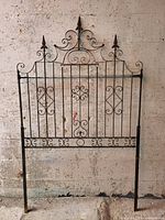 Full view of wrought iron panel against wall showing decorative scrollwork and spear finials