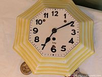 Front view of octagonal ceramic wall clock showing dial and hands