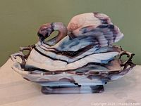 Full view of slag glass swan on nest, lid in place, showing marbled purple-white coloration and lattice base