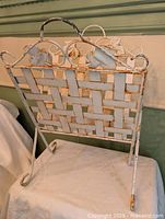 Full view of white woven metal magazine rack showing lattice panels, handle and feet