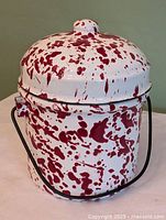 Front view of enamel splatter pot with lid and handle