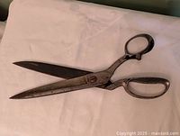 Full view of large metal scissors on cloth