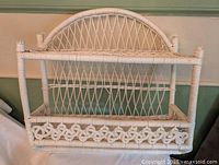 Front view of white wicker two-tier wall shelf showing overall design and condition