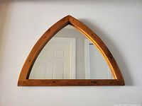 Front view of pine triangular mirror on wall