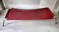Top view of red vinyl cot on metal frame