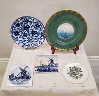 Group shot of all five items: two plates on stands, two windmill tiles and Ireland map trivet