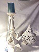 All three ceramic pieces grouped together: candlestick with blue candle, pierced jar, and star