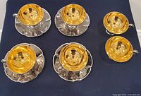 Top view showing six gold cups and four silver saucers
