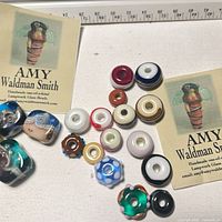 Beads laid out with two artist cards and measuring tape