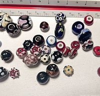 Group of assorted lampwork beads laid out showing quantity and variety