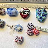 Group of lampwork beads under ruler showing variety of shapes and sizes