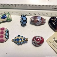 All seven glass beads laid out with ruler showing size reference