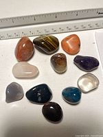 All eleven polished gemstones next to ruler for scale