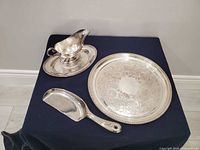 Overview of all four silver-plated pieces: round tray, gravy boat on underplate, serving scoop