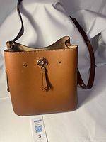 Front view of tan leather bucket purse showing strap and ring detail