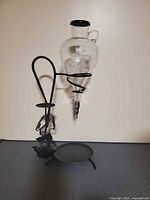 Full view of glass decanter mounted on iron stand