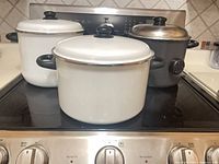Three stock pots with lids on stovetop