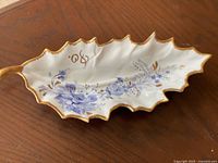 Top view of leaf-form Limoges dish with blue floral decoration and gilt edge
