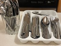 Mixed flatware grouped in plastic tray and glass holder
