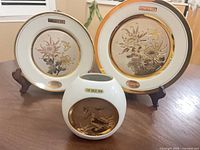 Two decorative plates on stands with vase in front